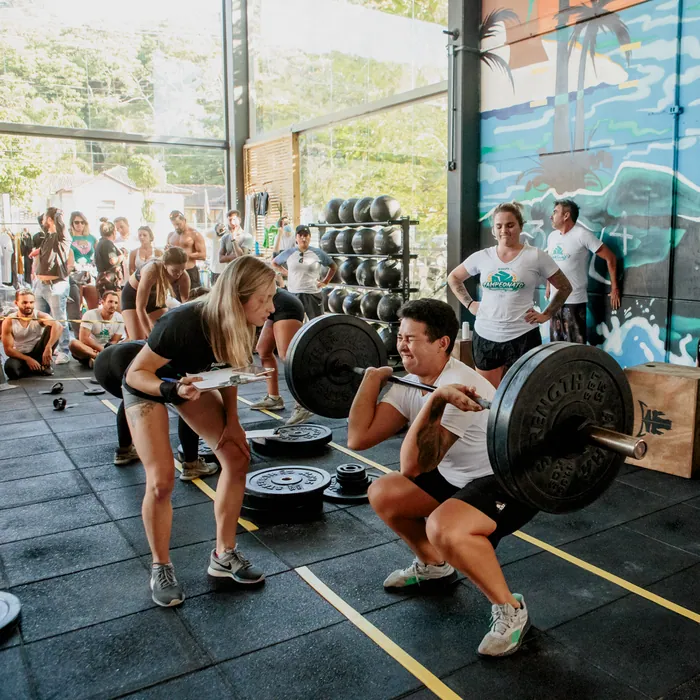 Aluna executando agachamento com barra durante treino de CrossFit em Florianópolis.