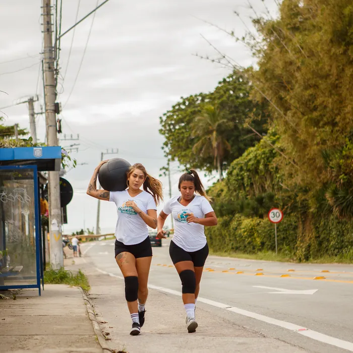 Alunas correndo na rua com medicine ball durante treino do CrossFit Morro das Pedras.