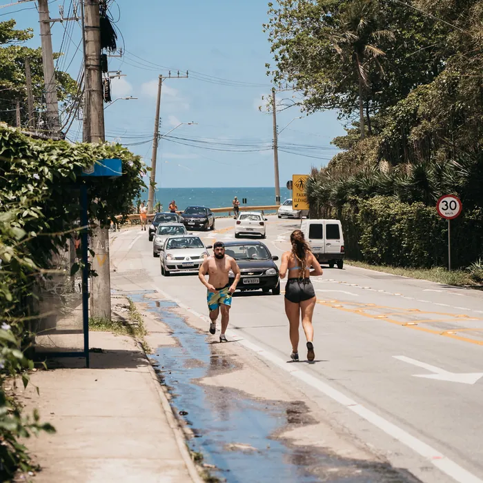 Alunos correndo pela rua em direção à praia do Morro das Pedras, em Florianópolis.
