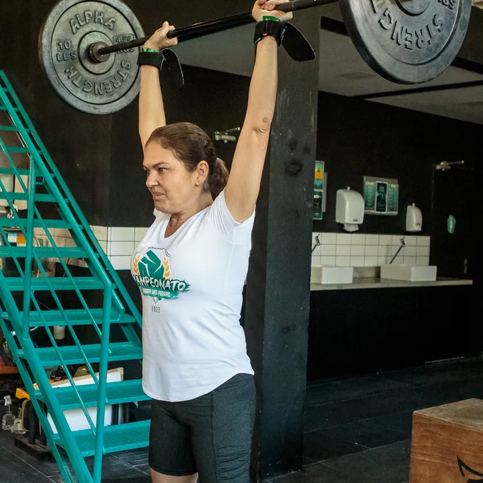 Aluna finalizando levantamento acima da cabeça no CrossFit Morro das Pedras.